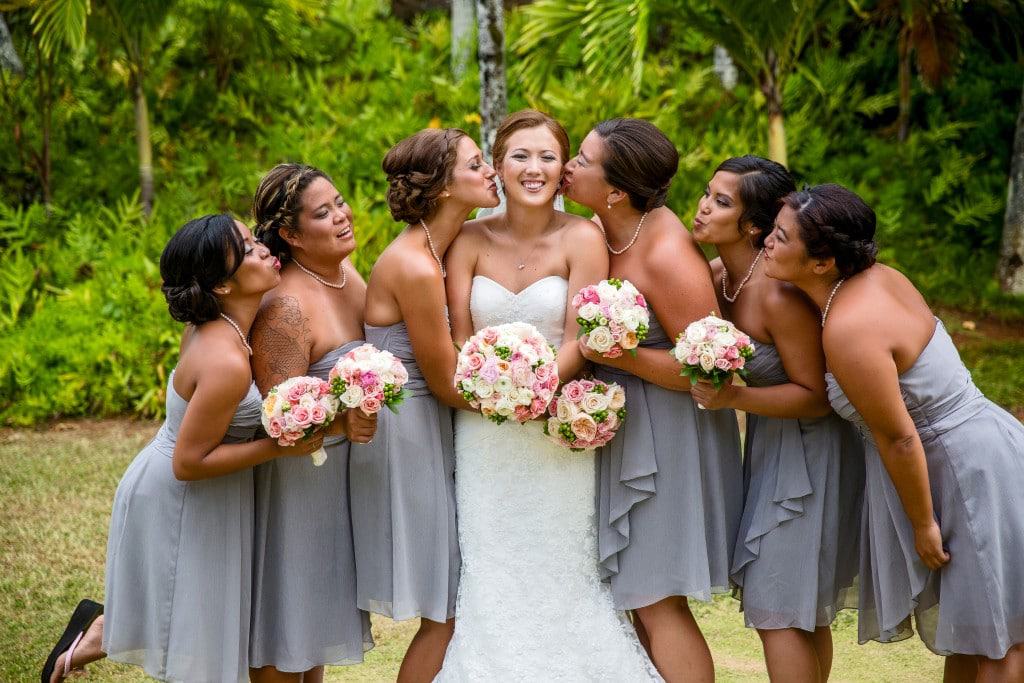 hawaii wedding bridesmaids kiss A bride and her bridesmaids are posing for a picture.