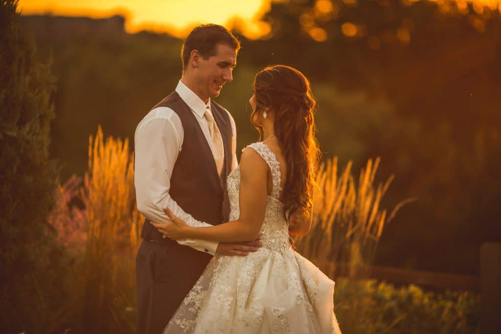 A bride and groom posing at Eau Claire Golf and Country Club during sunset.