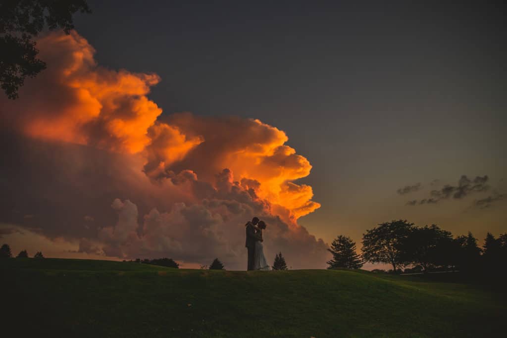 La Crosse WI Wedding Photographer captures newlyweds in front of a beautiful sunset cloud.