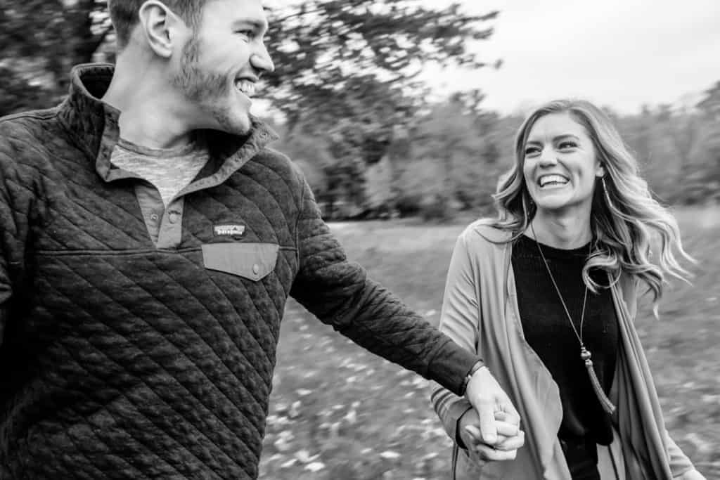 Perot State Park Engagement A black and white photo of an engaged couple walking through a field.