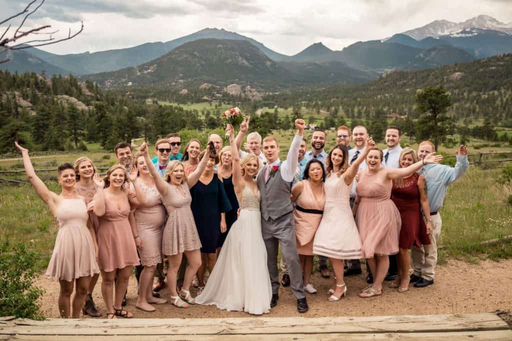 A group of bridesmaids and groomsmen pose for a photo in the mountains.