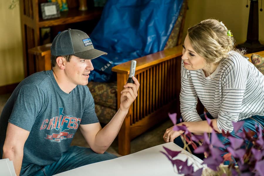 A man and woman sitting on a couch looking at a cell phone.