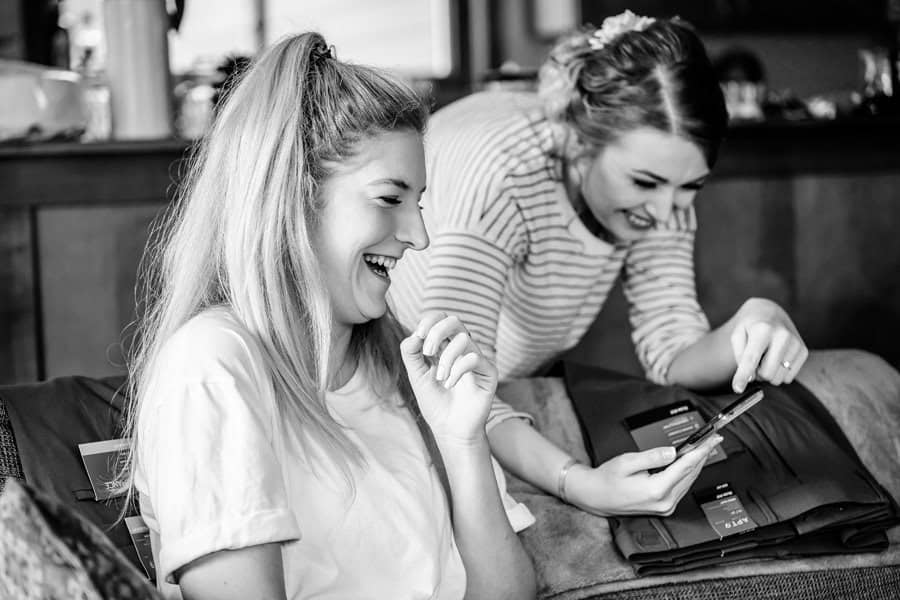 Two women looking at their phones while sitting on a couch.