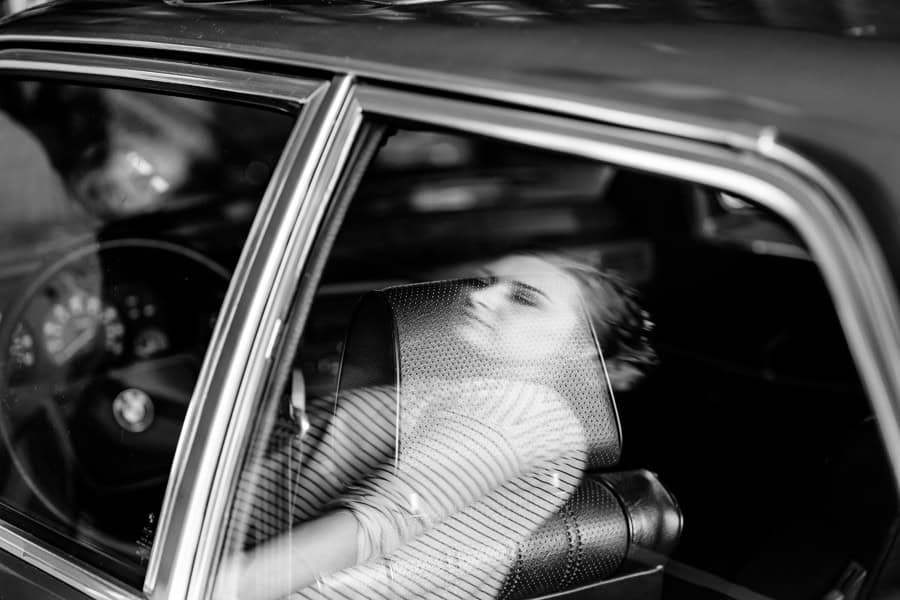 A black and white photo of a woman in a car.