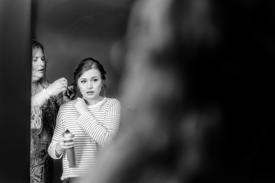 A woman is getting her hair done in front of a mirror.