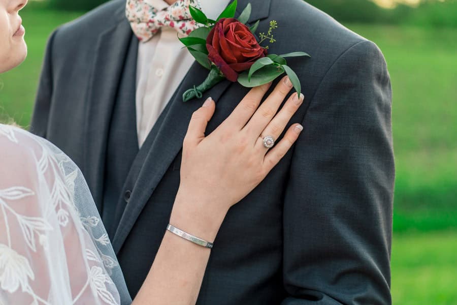 A bride and groom posing for a photo in a field.