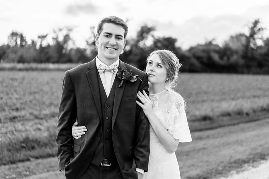 A bride and groom posing for a photo in a field.