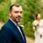James, wearing a suit, stands next to Courtney, the bride, in a love-filled backyard wedding.