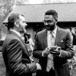 Two men in suits talking in front of Courtney and James' love-filled house.