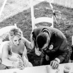 Black and white emotional photo of a group of people at a table at a backyard wedding in La Crosse.