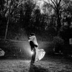 A love-filled backyard wedding in Trempleau captured in a black and white photo, featuring a bride and groom embracing in the rain.