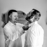 Black and white photo of Courtney and James putting on their ties at their love-filled Trempleau wedding.