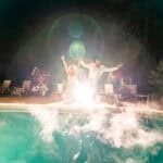 A group of emotional people jumping in the air by a pool during a backyard wedding in La Crosse.