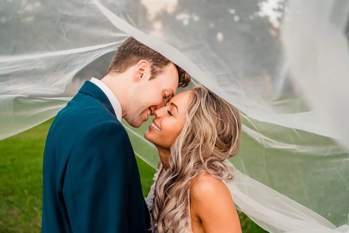 sunset photos waterfront riverside la crosse wi035 A bride and groom kiss under a veil.