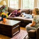 Two women sitting in a living room with a dog.