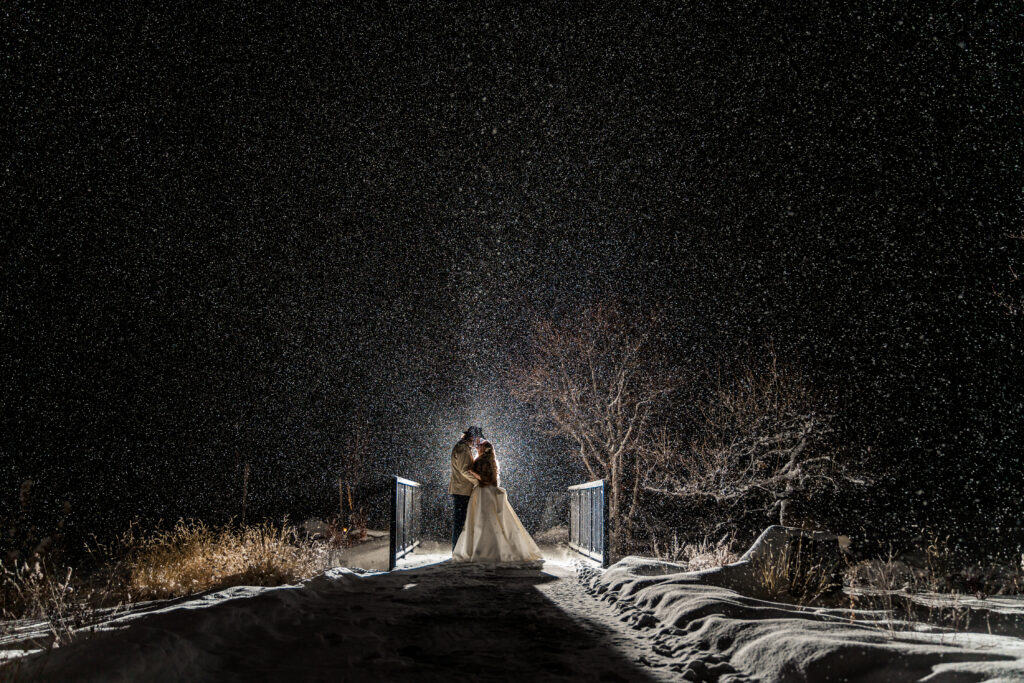 WilkWed_0813 A bride standing on a bridge in the snow at night.