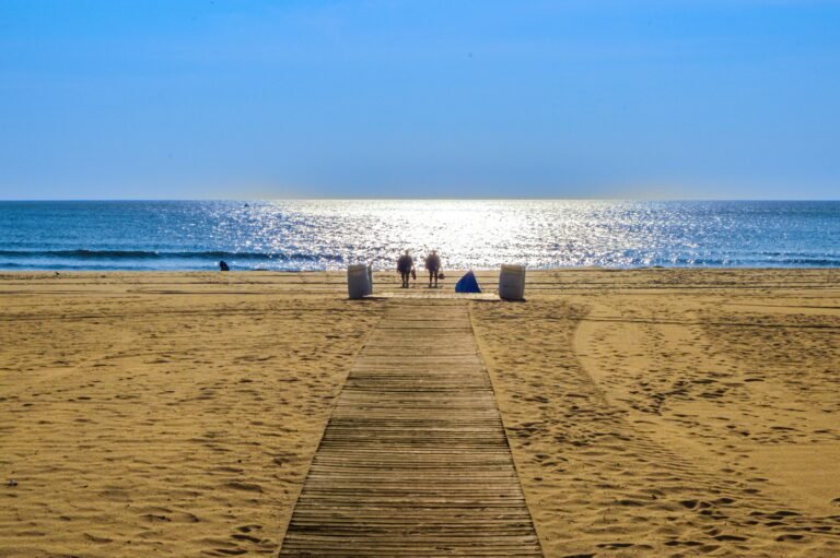 Wooden boardwalk leading across the sand to the sea at sunset, an accessible beach path