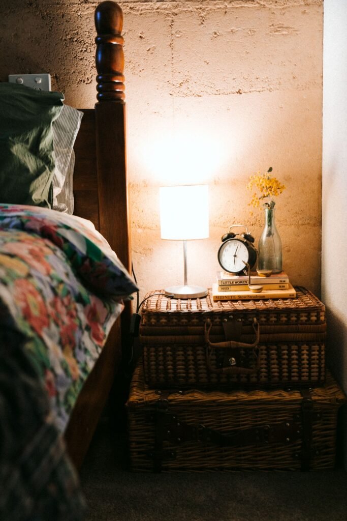 Bedside lamp glowing softly beside a bed in a dark bedroom at night
