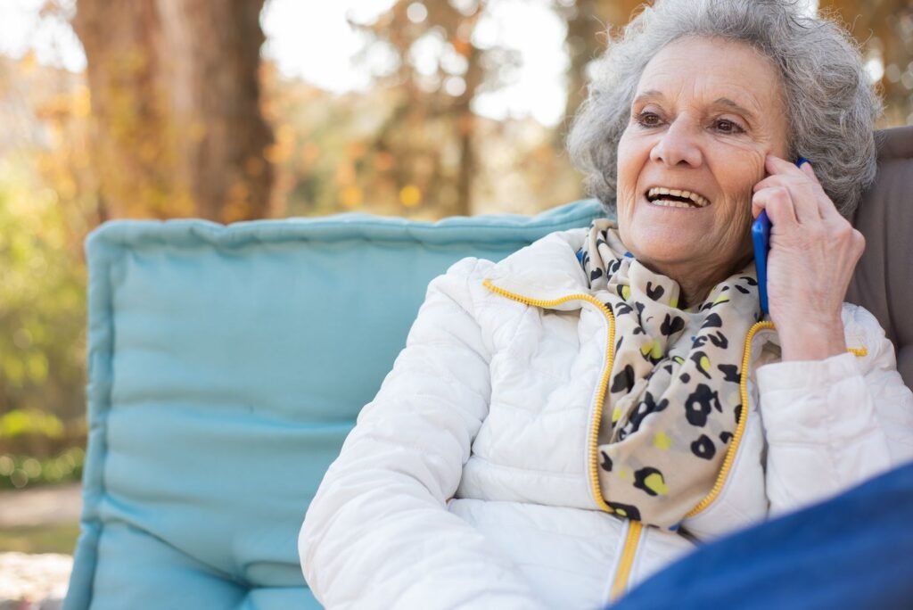 Smiling senior woman talking on the phone while sitting outdoors
