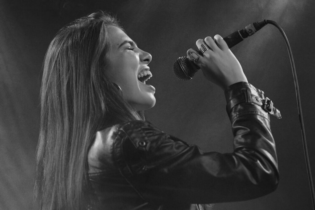 Female singer passionately singing into a microphone on stage.
