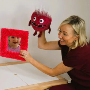 Child and therapist engaging with puppet in play therapy session.