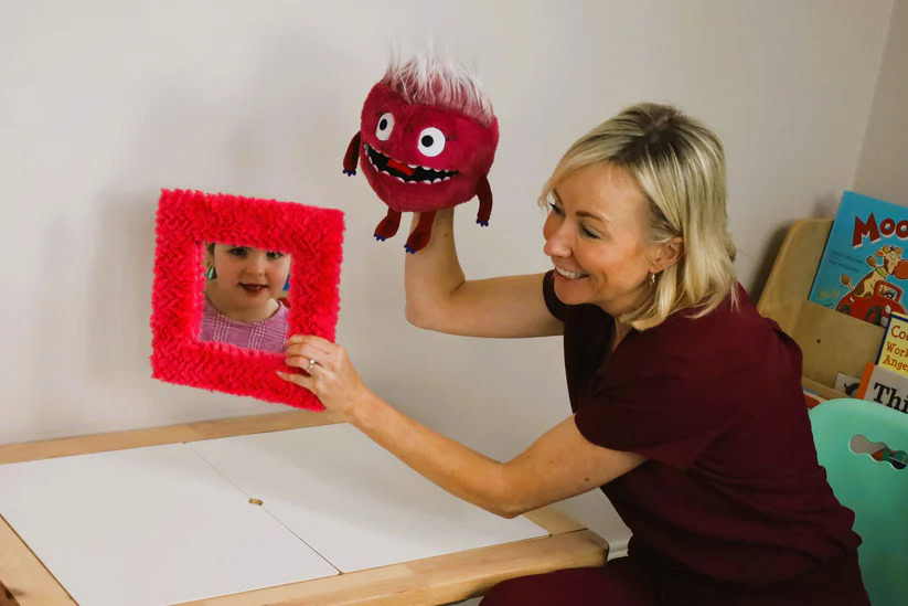 Child and therapist engaging with puppet in play therapy session.