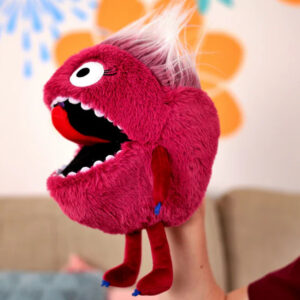 Colourful puppet with big eyes and open mouth, held up against a decorated background.