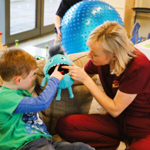 Child engaging in therapy with therapist using sensory toys and tools.