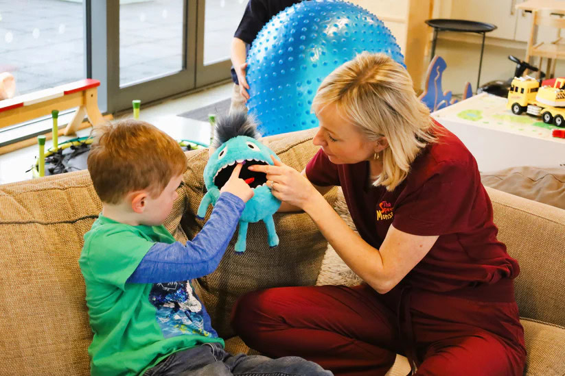 Child engaging in therapy with therapist using sensory toys and tools.