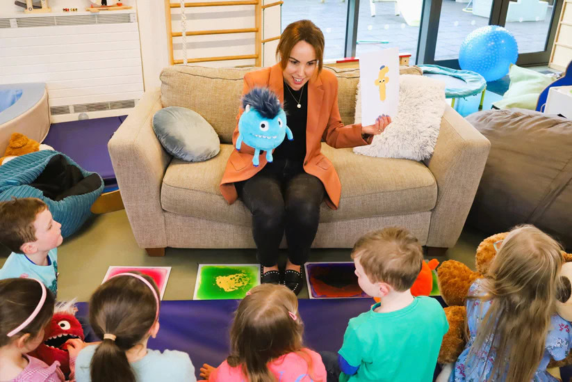 Woman leading a mindfulness session with children in a colourful therapy room.