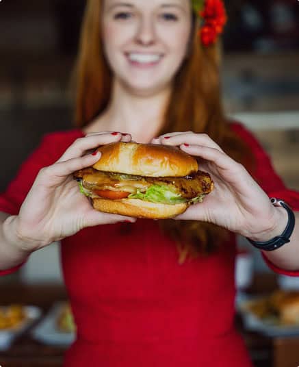 Woman holding a delicious burger with lettuce, tomato, and patty at The Burger Place Anaheim.
