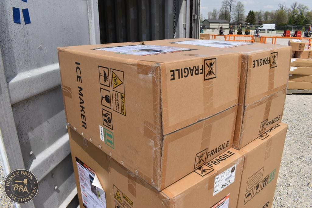 Stacked cardboard boxes with fragile and hazard labels at an auction yard.