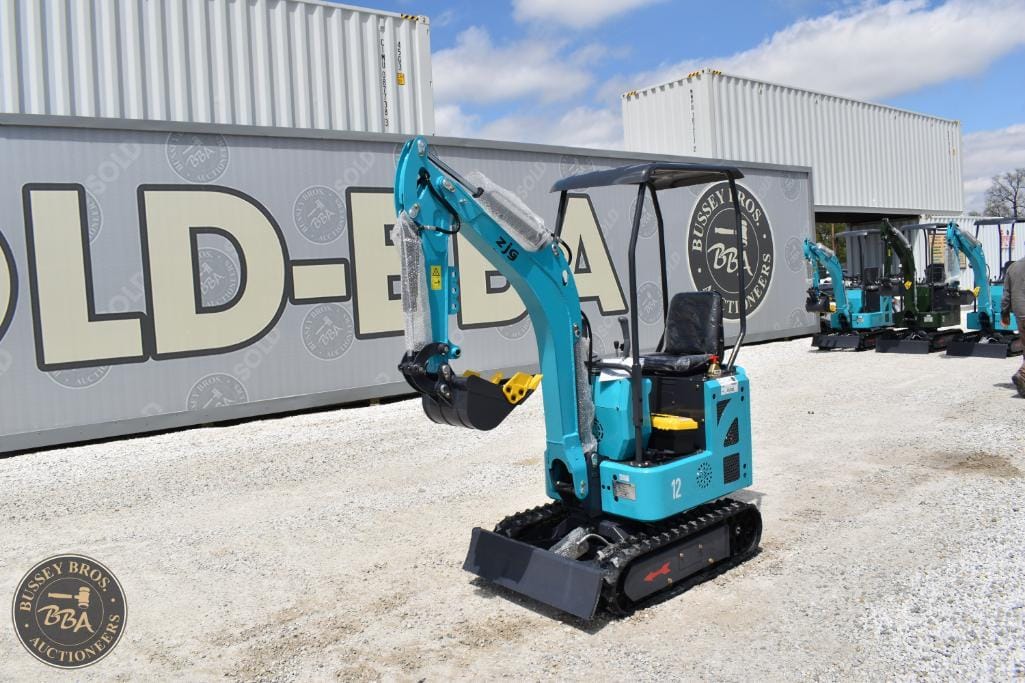 Mini excavator with blue body and black tracks, displayed outdoors at Bussey Bros Auctioneers.