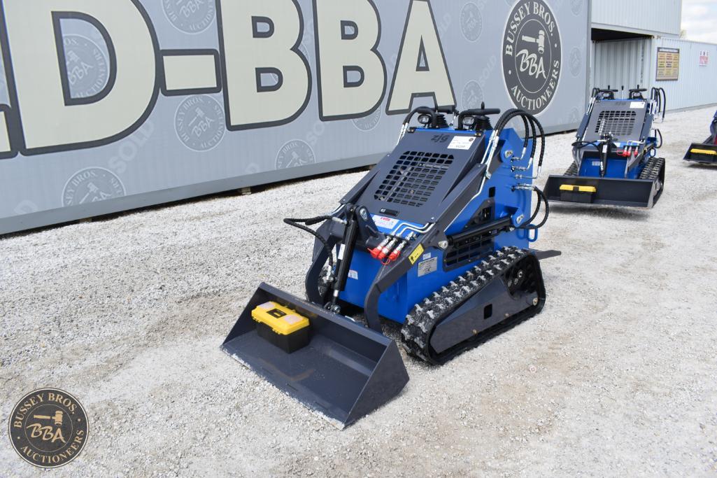 Compact blue mini excavator with tracked wheels and digging bucket, displayed outdoors at Bussey Bro.