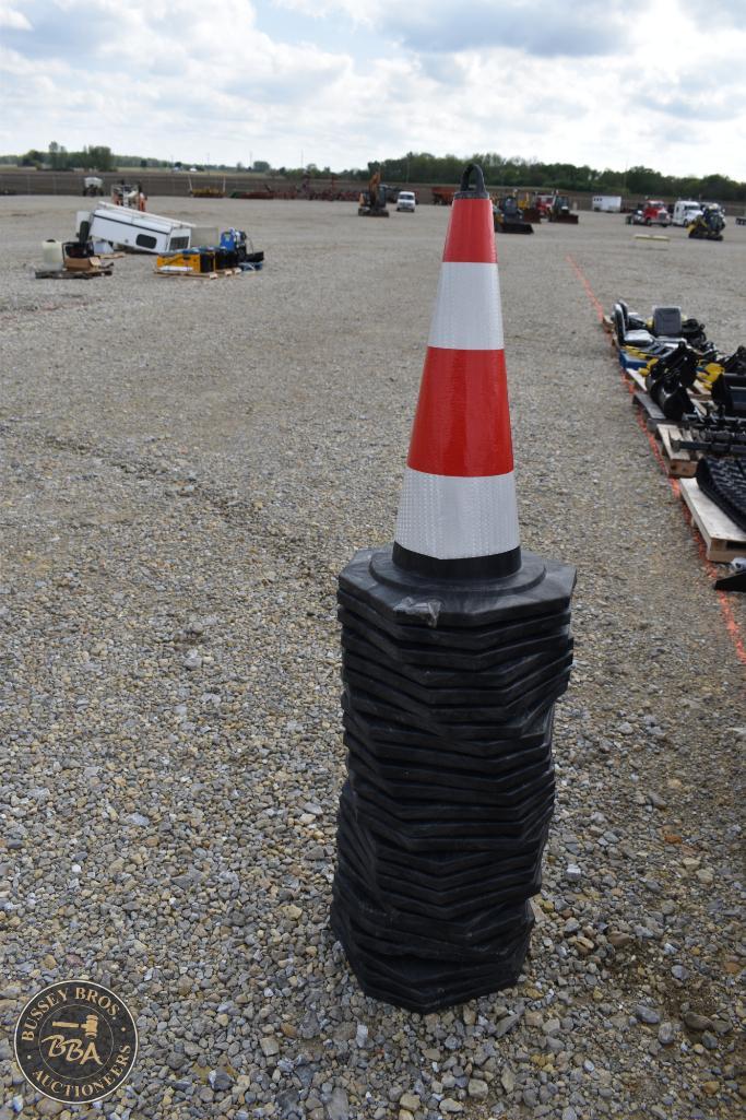 Traffic cone stacked on black rubber mats at an outdoor auction yard.