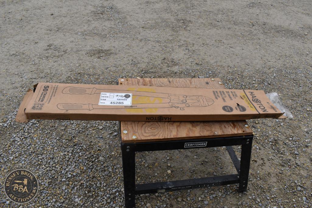 New garden hoe tool in packaging on a small wooden table outdoors.