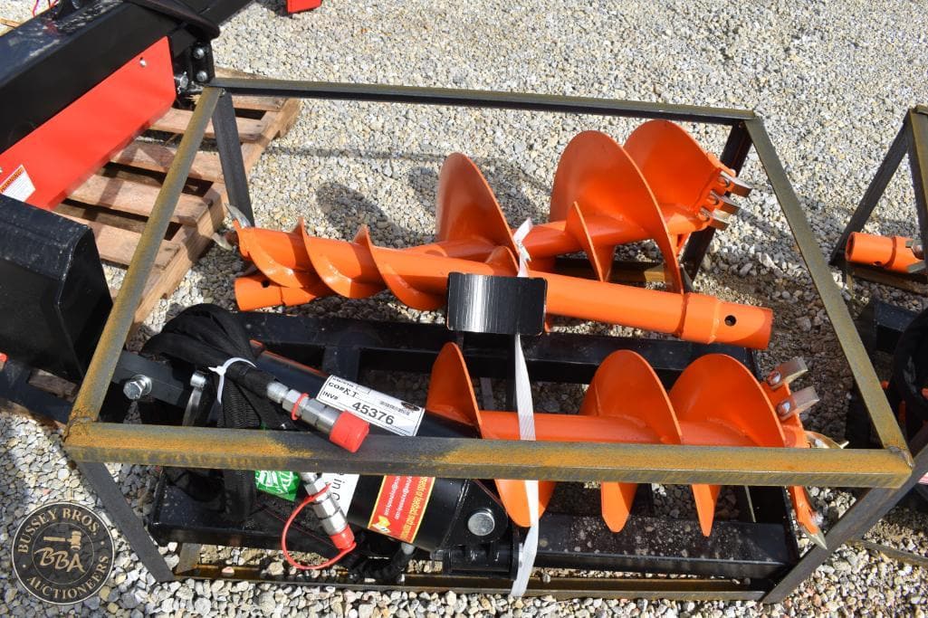 Earth auger drill bits in a metal frame at auction site.