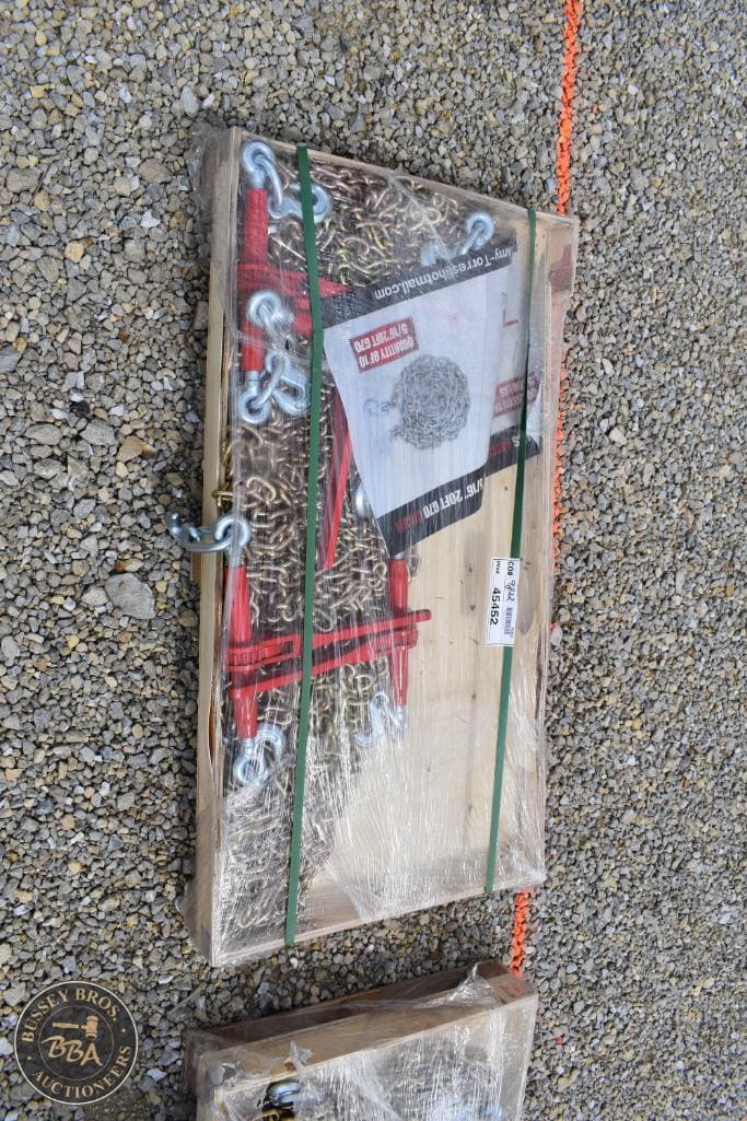 Auction equipment kit with chains, hooks, and tools on wooden board.