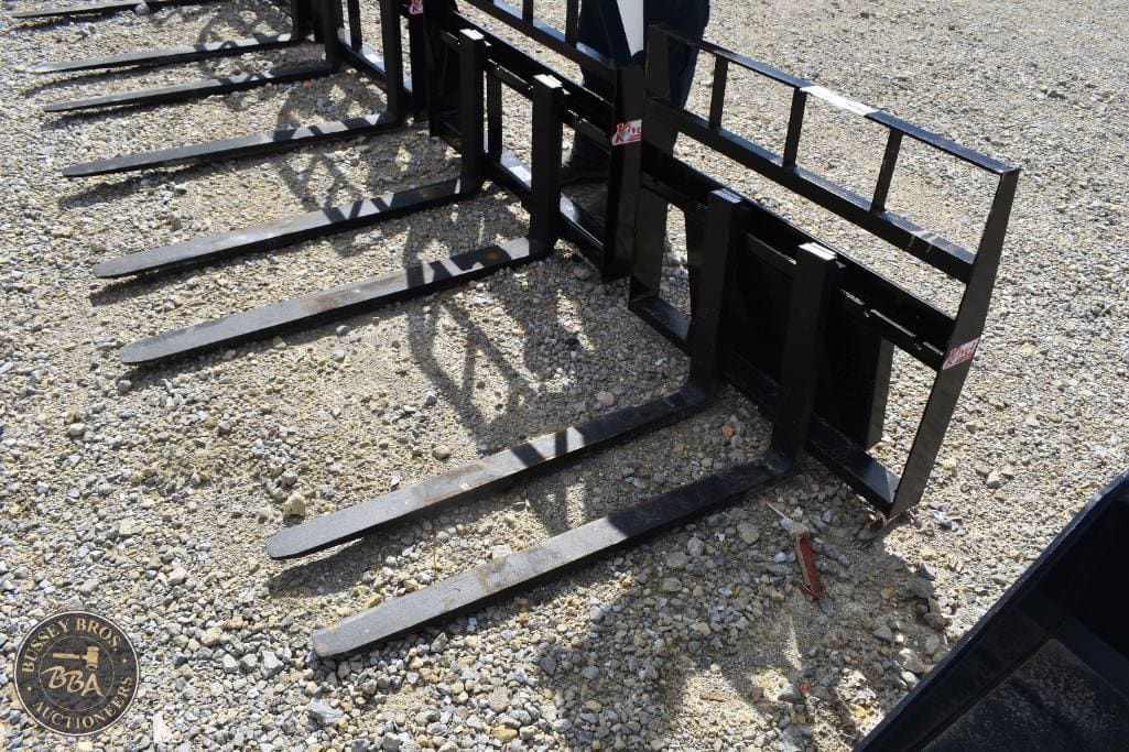 Forklift forks and attachments displayed outdoors at Bussey Bros Auctioneers.