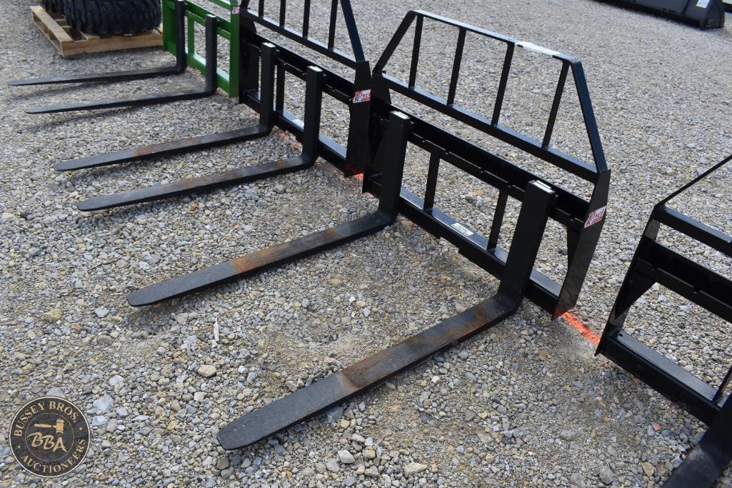 Forklift tines and attachments displayed outdoors at Bussey Bros Auctioneers.