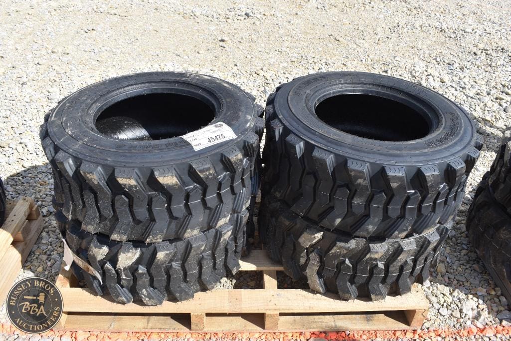 Heavy-duty off-road tires stacked on a pallet for auction.