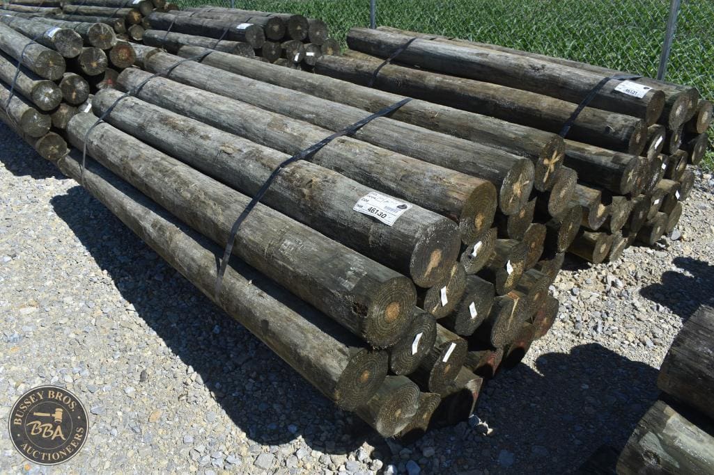Wooden logs stacked for auction at Bussey Bros Auctioneers, ideal for construction or landscaping pr.