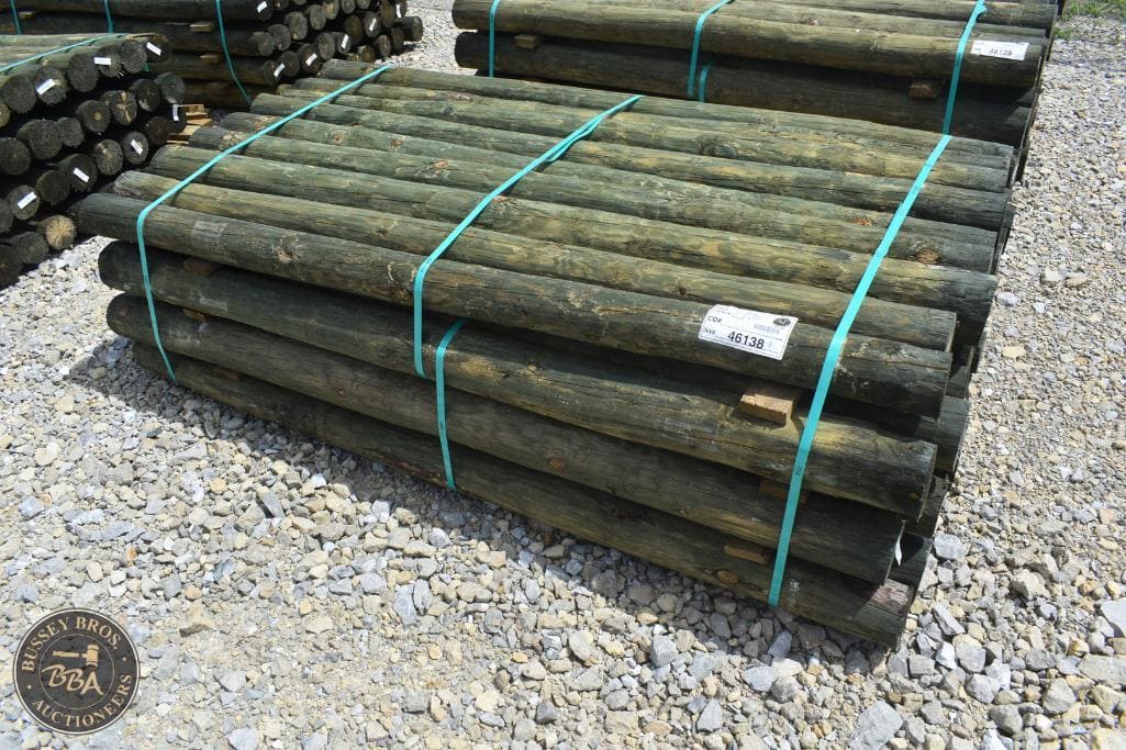 Wooden fence posts stacked and secured with blue straps at auction yard.
