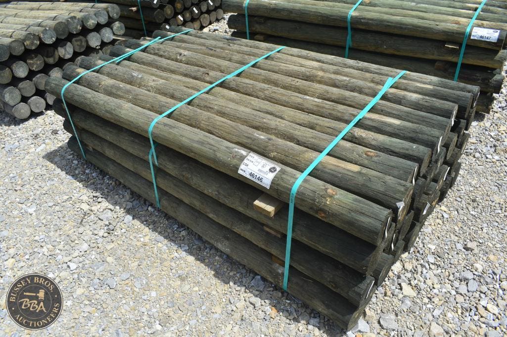 Stacked wooden fence posts for sale at Bussey Bros Auctioneers.