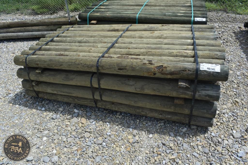 Stacked wooden fence posts available for auction at Bussey Bros Auctioneers.