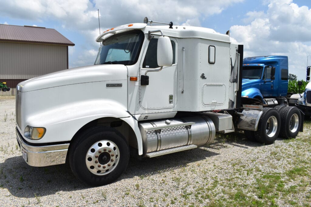 White semi truck parked outdoors at auction site.
