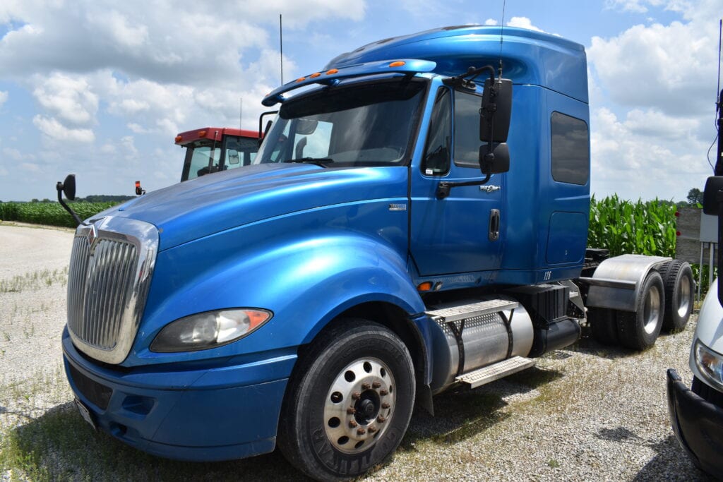 Blue semi truck at Bussey Bros Auction with clear sky background.