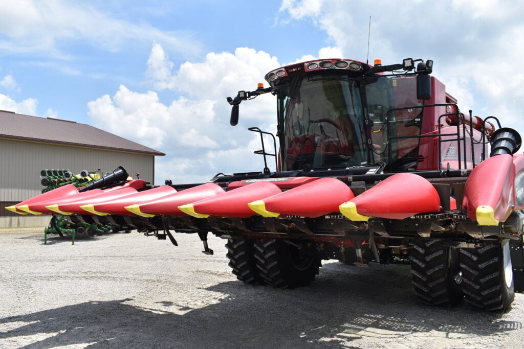 Large red and black combine harvester at farm auction event.