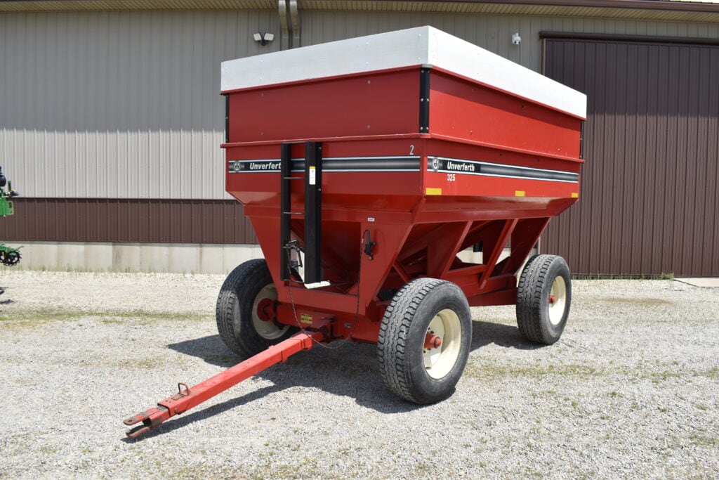 Red farm fertilizer spreader with wheels at auction site.