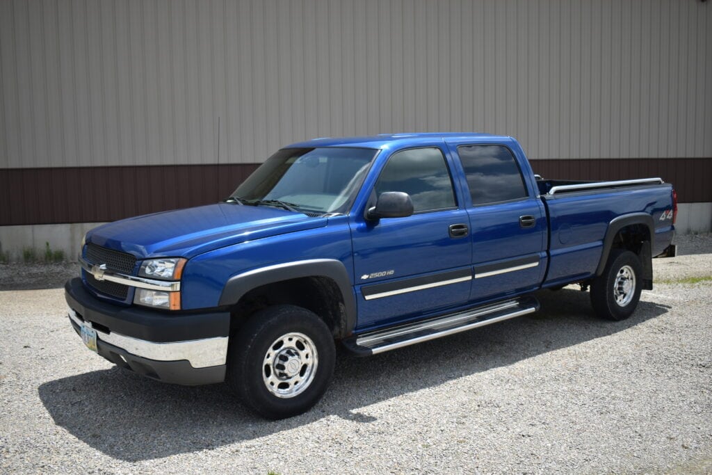Blue Chevrolet Silverado pickup truck parked outside at a farm auction.